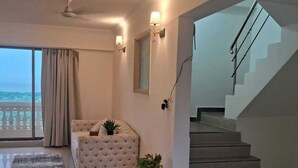 Ein modernes Wohnzimmer mit einer Couch, einer Topfpflanze und einer Treppe, die in einen oberen Bereich führt.