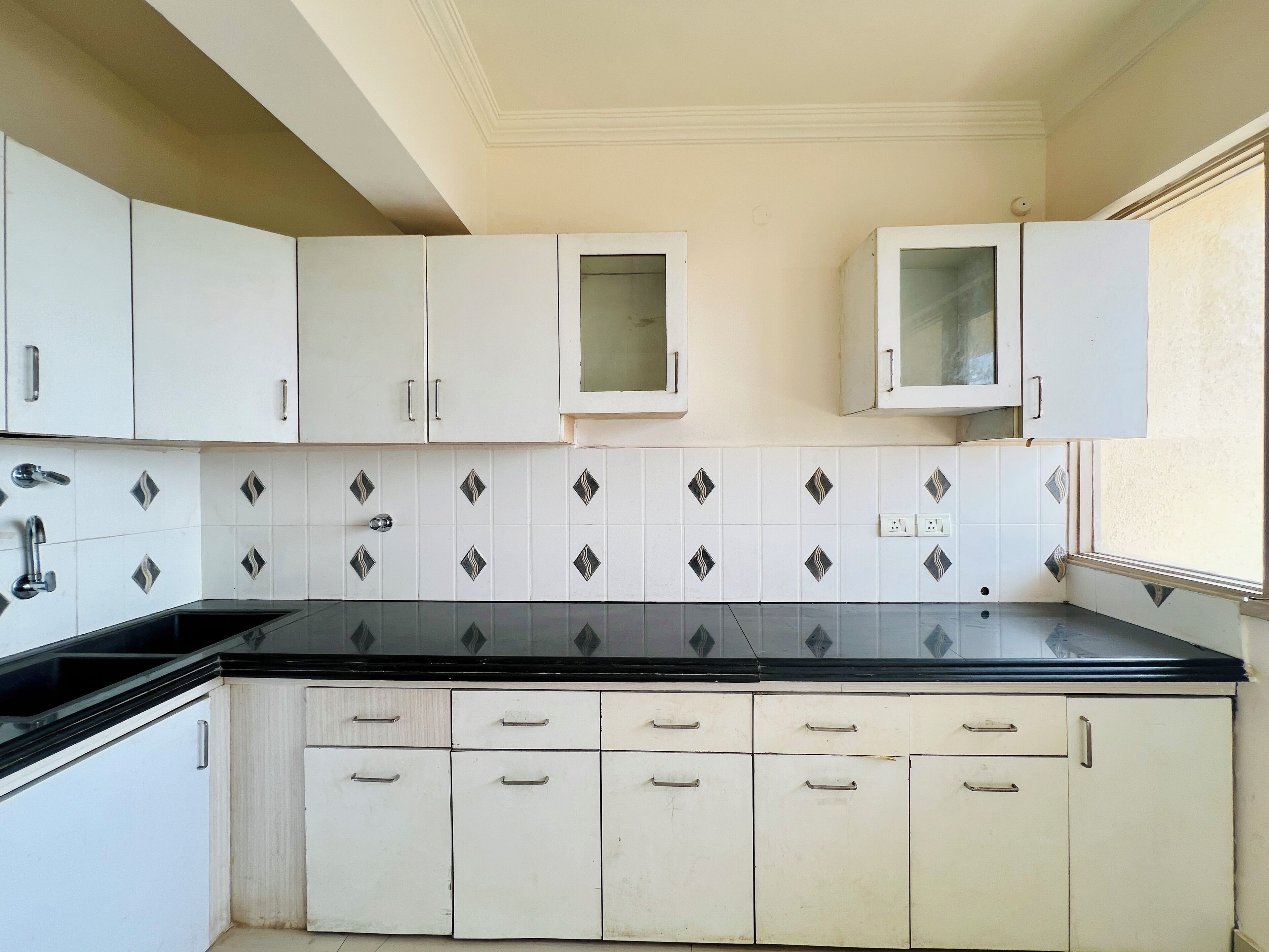 A kitchen with white cabinets, a black countertop, and a tiled backsplash.