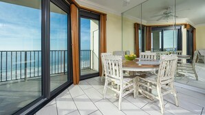 Ein Balkon mit Meerblick, ein Esstisch mit Stühlen und ein Deckenventilator.