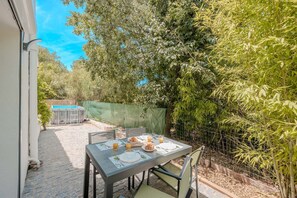 Eine Terrasse mit Tisch für zwei Personen, umgeben von üppiger Vegetation und einem Bambuszaun.