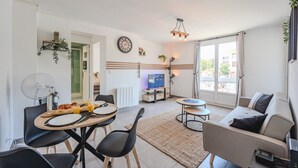 A modern living room with a dining area, a sofa, a TV, and a large window. - The Port Marchand Escapade - Air-conditioned flat (Toulon)