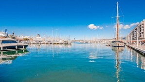 A marina with boats docked, a tall sailboat, and a building with balconies. - The Port Marchand Escapade - Air-conditioned flat (Toulon)