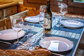 A dining table set with plates, glasses, and a bottle of wine, with a loaf of bread on the table. - Entire chalet, panoramic views, stream and sauna. (Bussang)