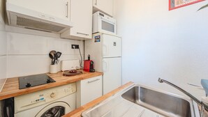 A compact kitchen with a washing machine, a microwave, a toaster, and a sink. - Charming Apartment - Panoramic Harbor View (La Seyne-sur-Mer)