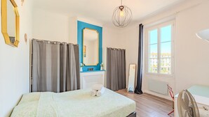A bedroom with a bed, a dresser, a mirror, a window, and a fan. - Charming Apartment - Panoramic Harbor View (La Seyne-sur-Mer)