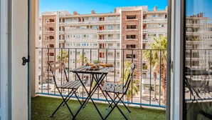 Un balcón con una mesa y sillas, con vista a una hilera de edificios de varios pisos con balcones.