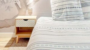 A bedroom with a bed, pillows, a nightstand, and a wall decoration.