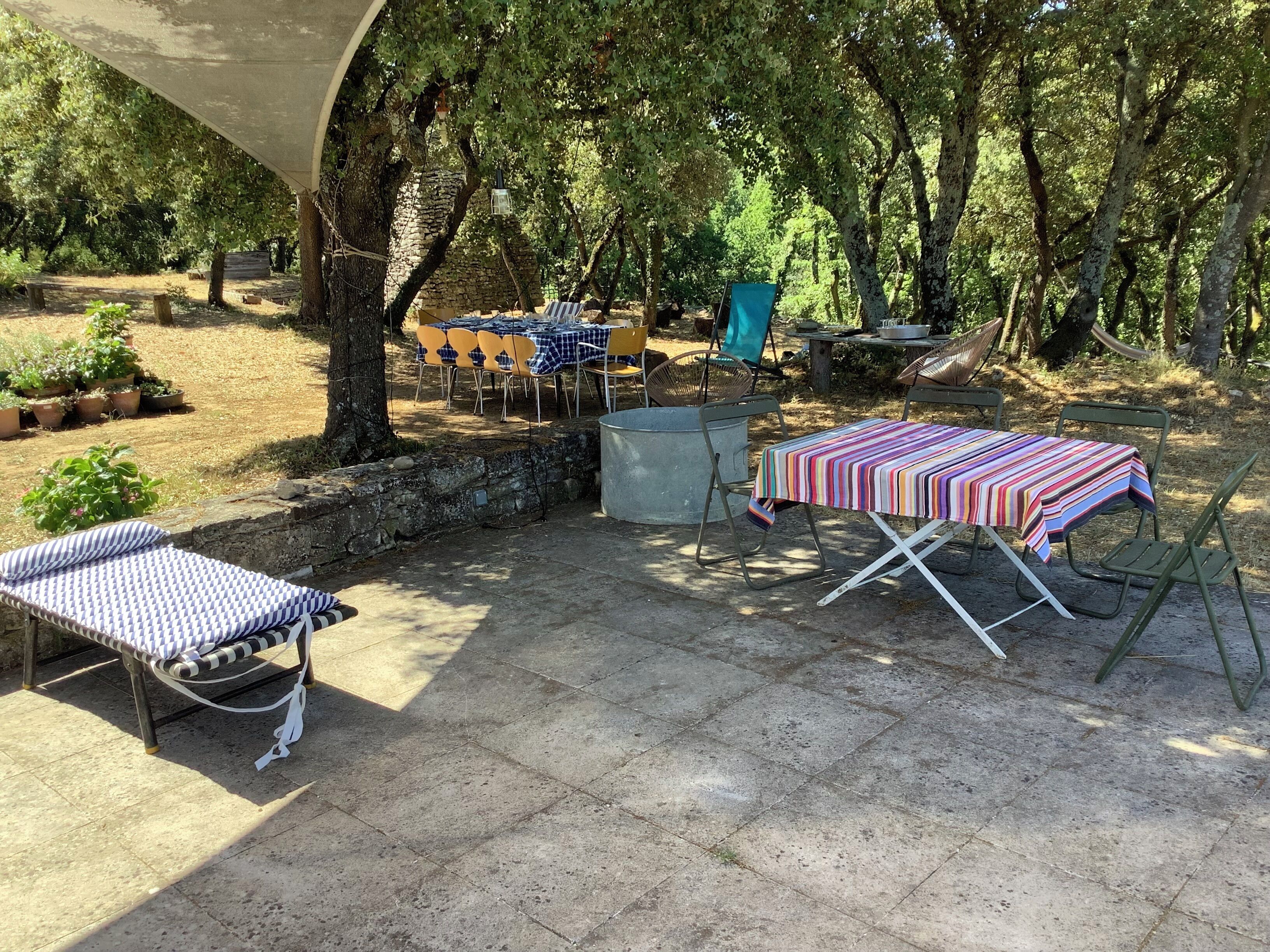 Ein Außenbereich mit Terrasse, Tisch, Stühlen, einer Hängematte und Topfpflanzen.