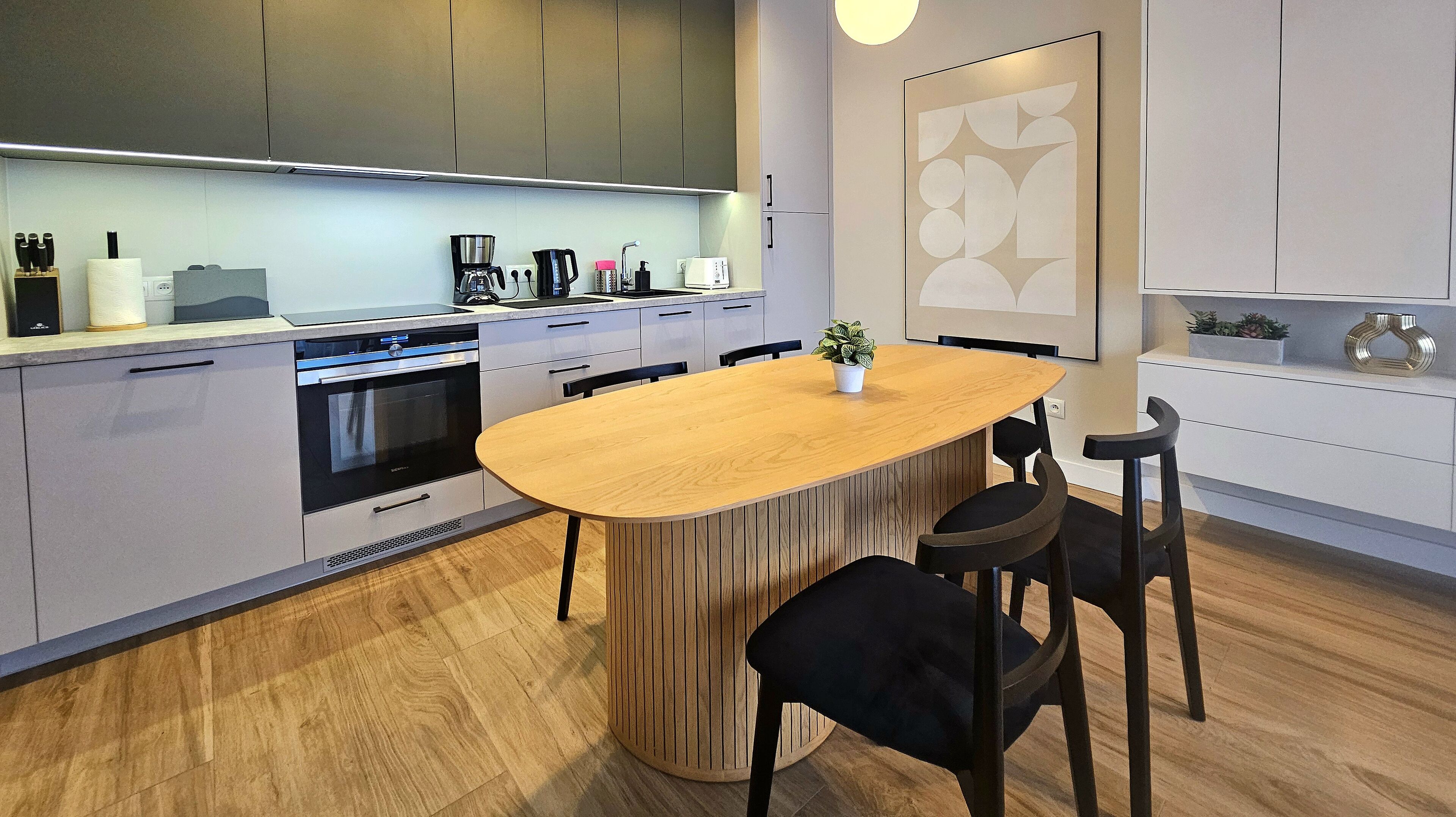 Una cocina moderna con una isla central, electrodomésticos integrados y un comedor con sillas.