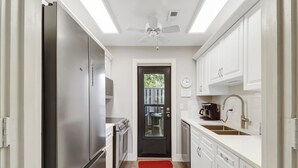 A modern kitchen with a refrigerator, stove, sink, and a clock on the wall. - Cozy Beach Retreat with Tennis! Short walk to the beach! (Hilton Head Island)