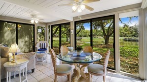 A conservatory with a glass table, wicker furniture, and a ceiling fan. - Cozy Beach Retreat with Tennis! Short walk to the beach! (Hilton Head Island)