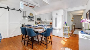 A spacious kitchen with white cabinetry, a central island with bar stools, and a ceiling fan. - CASA DEL SUR ~ Renovated 2 BR/2Ba Home with Heated Dip Pool! (Key West)