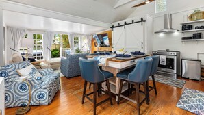 A spacious living area with a wooden dining table, blue upholstered chairs, and a large TV. - CASA DEL SUR ~ Renovated 2 BR/2Ba Home with Heated Dip Pool! (Key West)