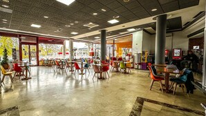 A spacious indoor area with multiple tables and chairs, large windows, and a variety of seating options.