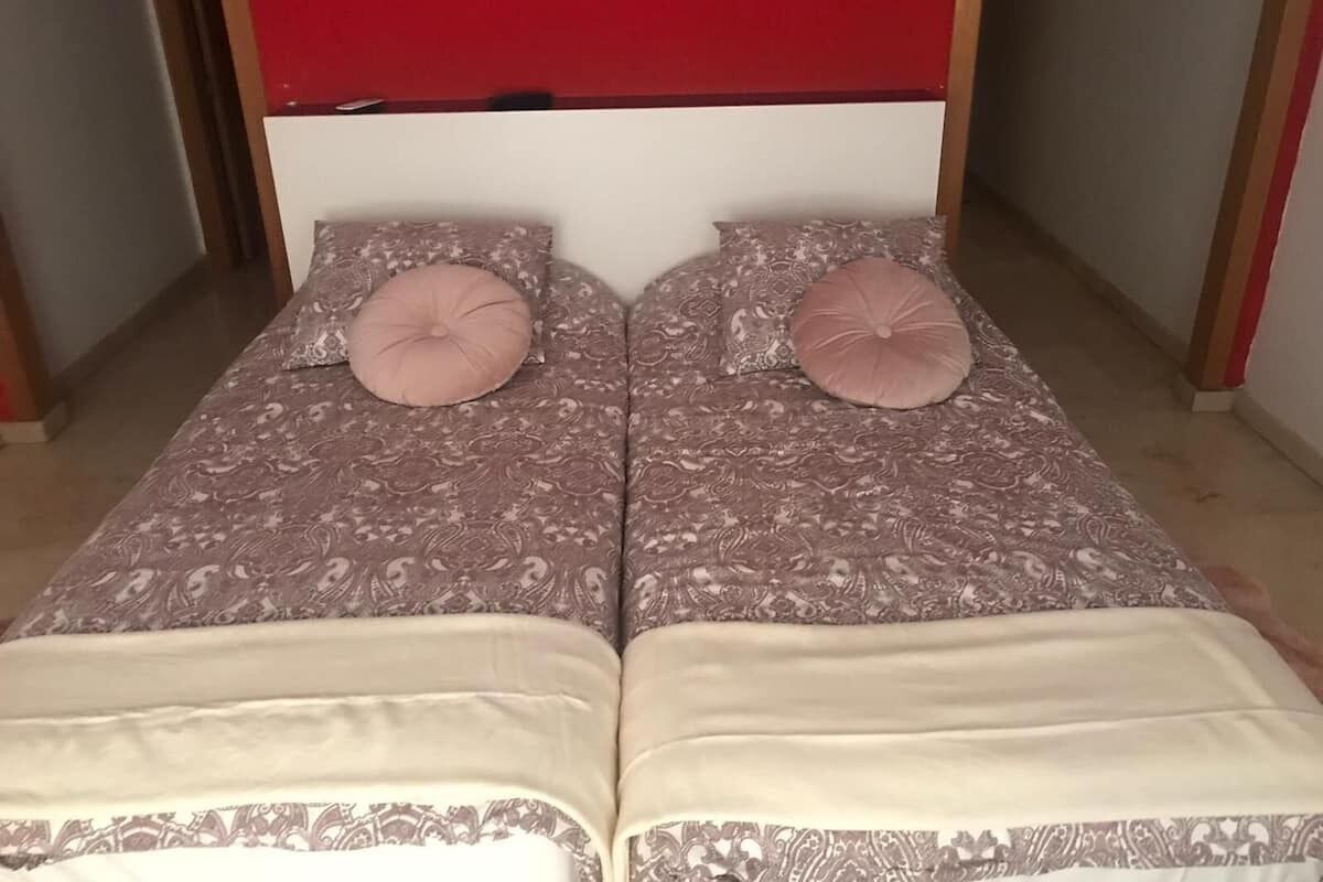 A double bed with a patterned bedspread and two matching pillows.