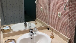 A bathroom with a sink, two hair dryers mounted on the wall, a mirror, and a shower curtain.