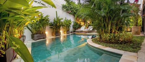 Una piscina al aire libre, sillones reclinables de piscina