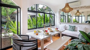 A dining area with a white table, black wicker chairs, and a white sofa. - Villa Roma (Seminyak)