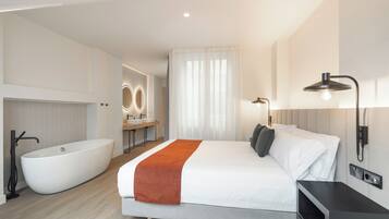 Ein modernes Hotelzimmer mit einem großen Bett, einem separaten Badezimmer mit Badewanne und einem Schminktisch mit Spiegel.