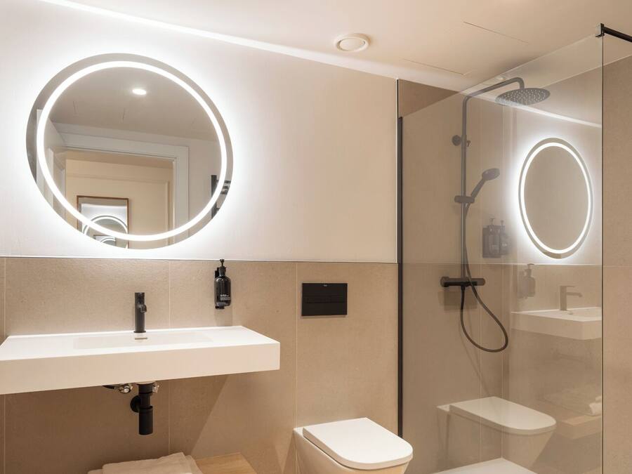 Une salle de bain moderne avec un lavabo blanc, des toilettes et une douche séparée par une paroi en verre.