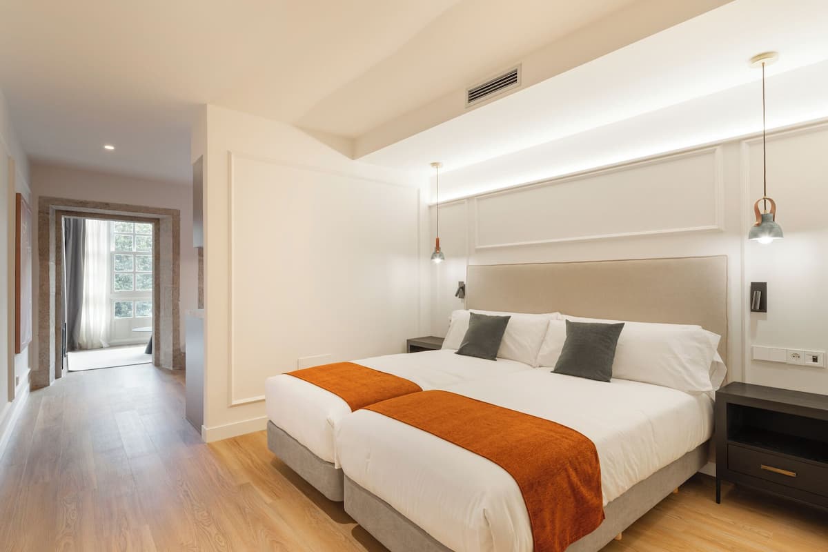 A bedroom with a large bed, bedside tables, a nightstand, a window, and a door.