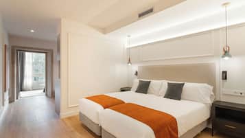Un dormitorio con una cama grande, mesitas de noche, una mesilla auxiliar, una ventana y una puerta.