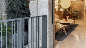 A modern hotel lobby with a stone facade, a reception desk, and a seating area with a round table and chairs. - Marina 30 (A Coruña)