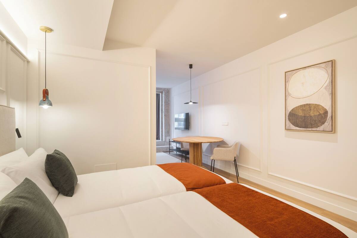 A modern hotel room with a large bed, a small dining table, and a TV.