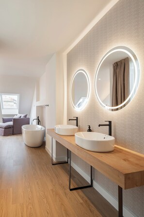 A modern bathroom with two round sinks, a large mirror with integrated lighting, and a wooden vanity. - Marina 30 (A Coruña)