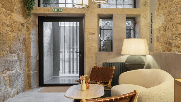 A cozy interior with a stone wall, a wooden table with chairs, a lamp, and a large bean bag. - Marina 30 (A Coruña)