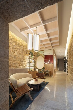A modern interior with a stone wall, a sofa, a coffee table, and a wooden chair. - Marina 30 (A Coruña)