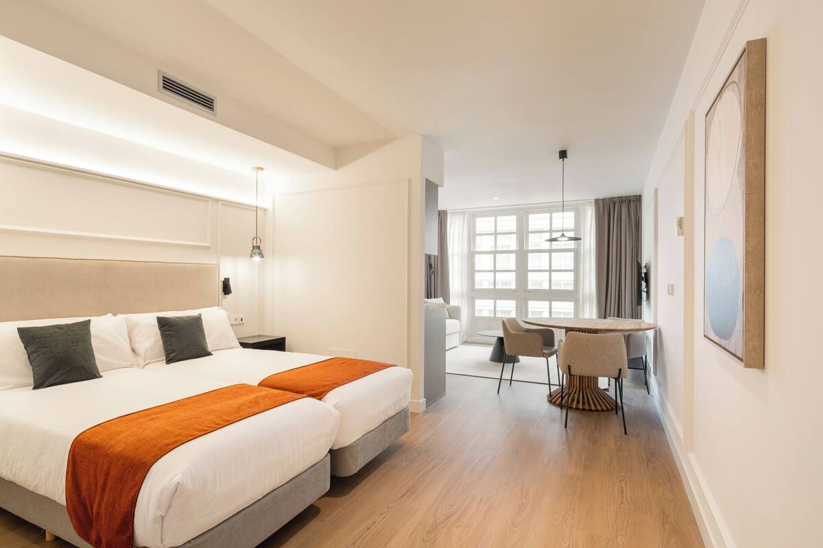 A hotel room with a large bed, a desk, and a chair.
