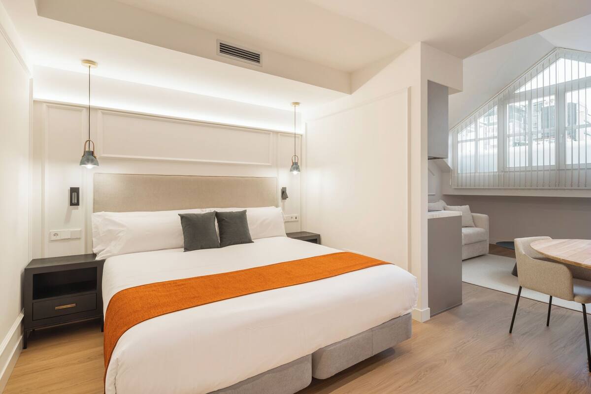 A modern hotel room with a large bed, bedside tables, a desk, and a chair.