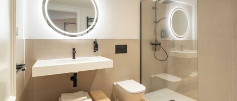 A modern bathroom with a white sink, a toilet, and a glass-enclosed shower area.