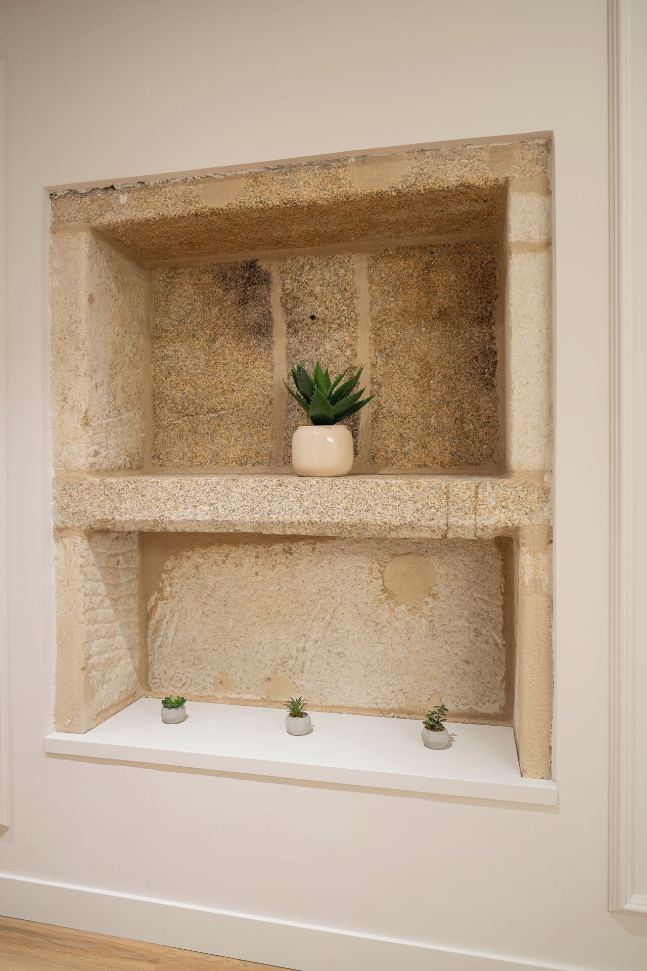 Uma prateleira de pedra com três vasos de plantas.