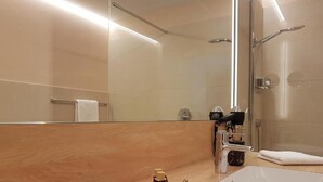 A modern bathroom with a large mirror, a shower, and a vanity with toiletries. - Restaurant & Hotel Einhorn (Oppenweiler)