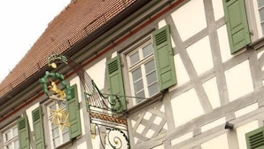 A traditional half-timbered building with green shutters, a red door, and a decorative metal staircase. - Restaurant & Hotel Einhorn (Oppenweiler)