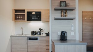 Una cocina moderna con armarios de madera, microondas integrado, cafetera y hervidor.