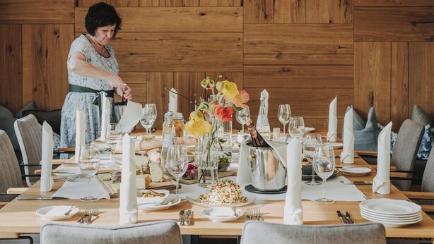 Comedor con paneles de madera, con una mesa dispuesta para una comida, incluyendo platos, vasos y una botella de champán.