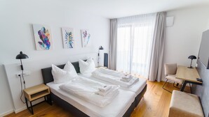 Ein modernes Hotelzimmer mit einem großen Bett, einem Schreibtisch und einem Sessel.