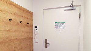 Ein Flur mit einer Holzbank, einer weißen Tür mit einem Schild und einem an der Wand montierten Telefon.