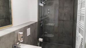 Ein modernes Badezimmer mit einem weißen Waschbecken, einer Toilette und einer gläsernen Dusche.