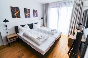 Een hotelkamer met twee bedden, een bureau, een stoel, een televisie en kunst aan de muur.