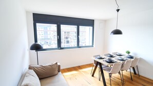 Ein Essbereich mit Holzboden, einem für vier Personen gedeckten Tisch und einem Fenster mit Jalousien.