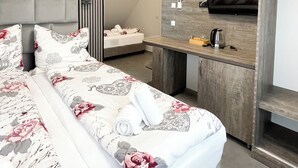 A modern hotel room with a large bed, a wooden desk, a flat-screen TV, and a built-in wardrobe. - Hotel Löwenstein (Lich)