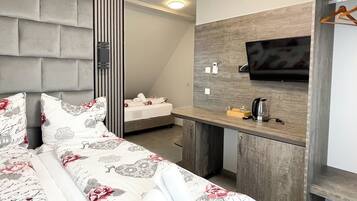 Ein modernes Hotelzimmer mit einem großen Bett, einem Holztisch, einem Flachbildfernseher und einem integrierten Kleiderschrank.