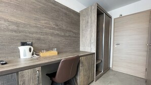 A compact, modern room with a built-in desk, a chair, a coffee maker, and a trash bin. - Hotel Löwenstein (Lich)
