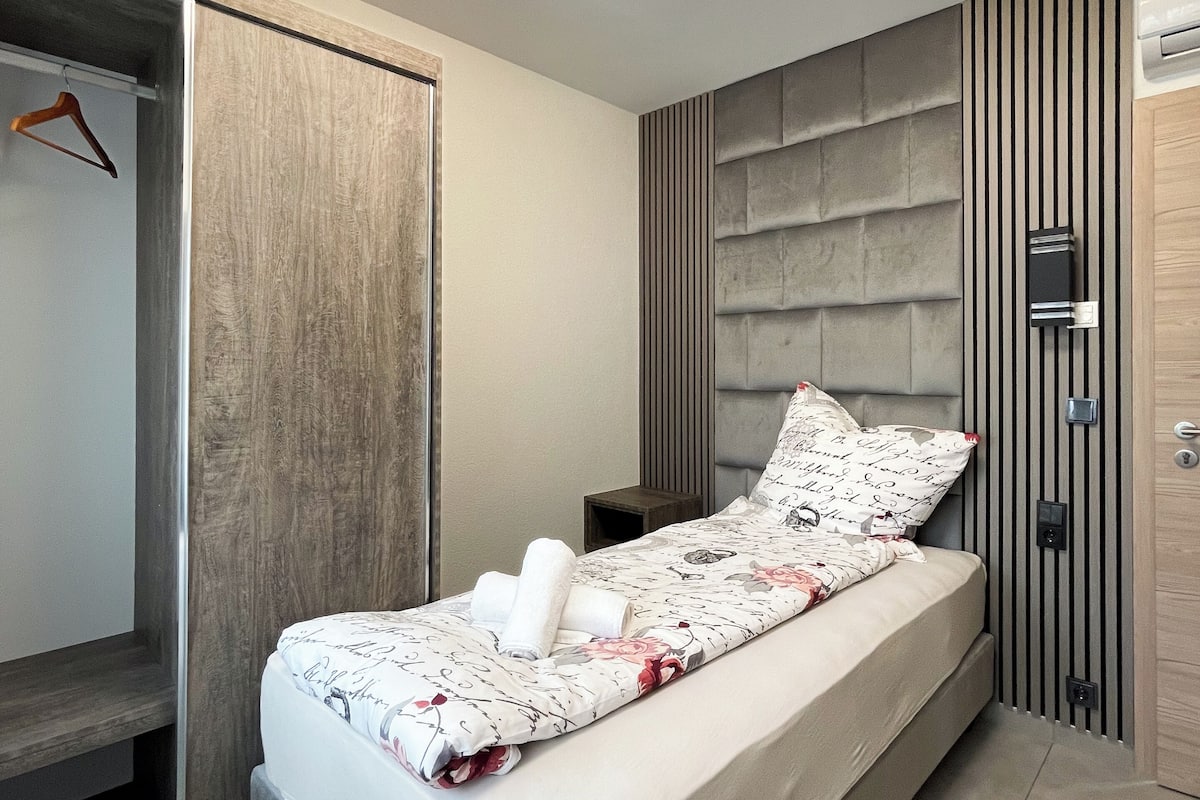 A modern bedroom with a bed, a wardrobe, and a built-in bench.