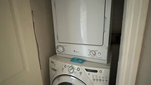 Un espacio de lavandería compacto con lavadora de carga frontal y secadora apilada.