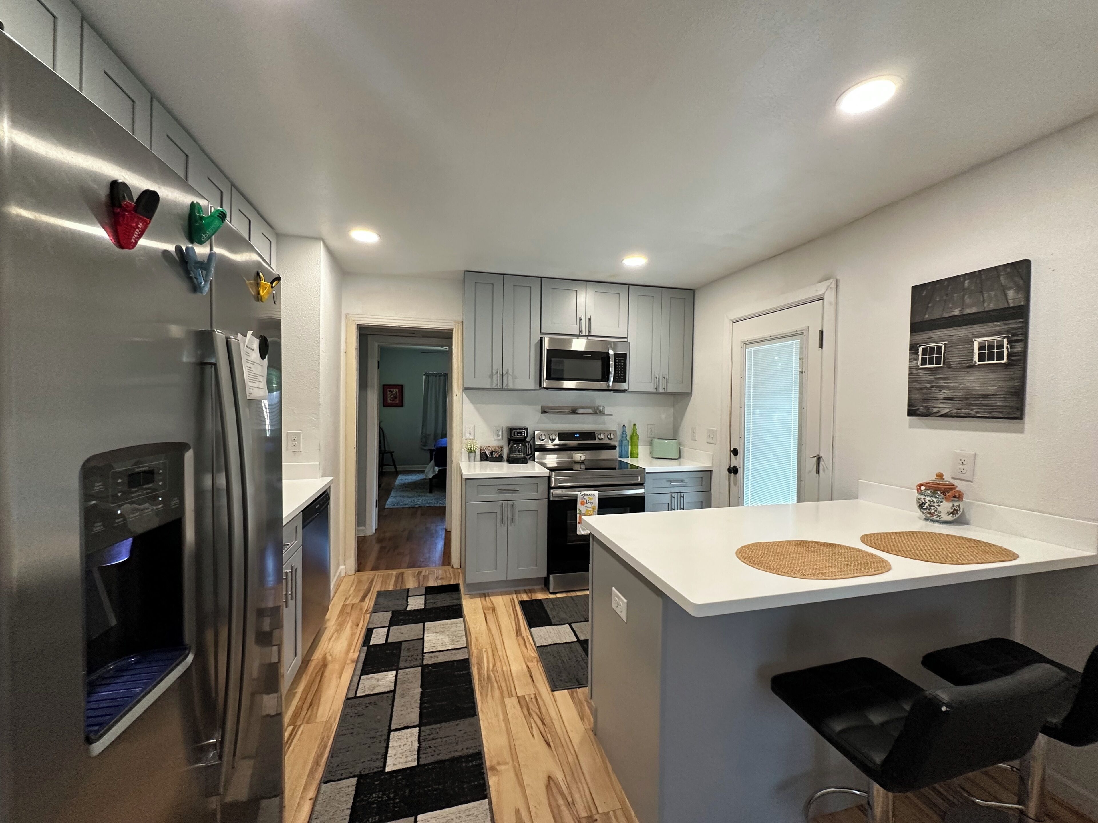A modern kitchen with stainless steel appliances, grey cabinets, and a central island with bar stools.